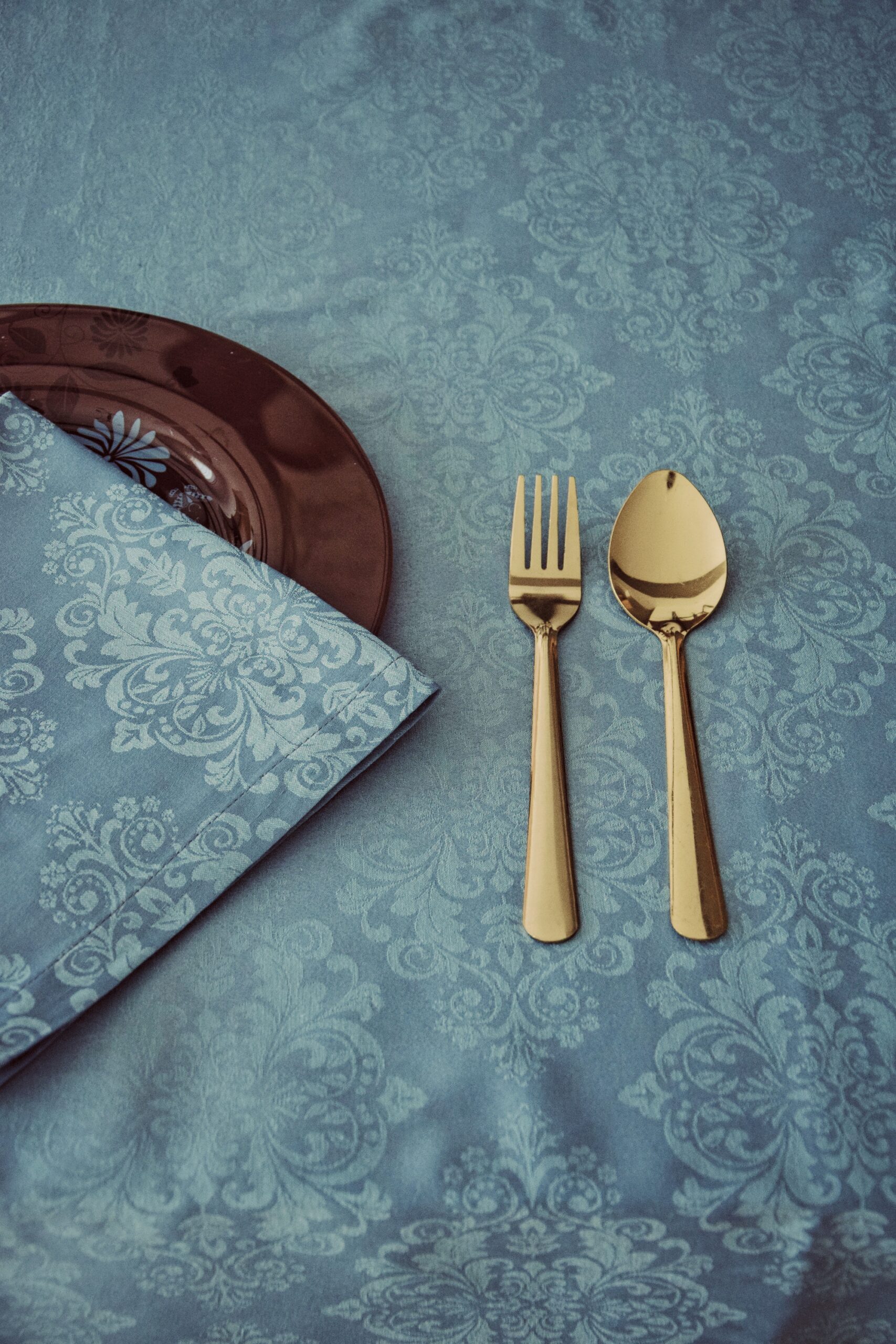 Nappe et serviette de table bleu motif baroque avec couverts dorés et assiette