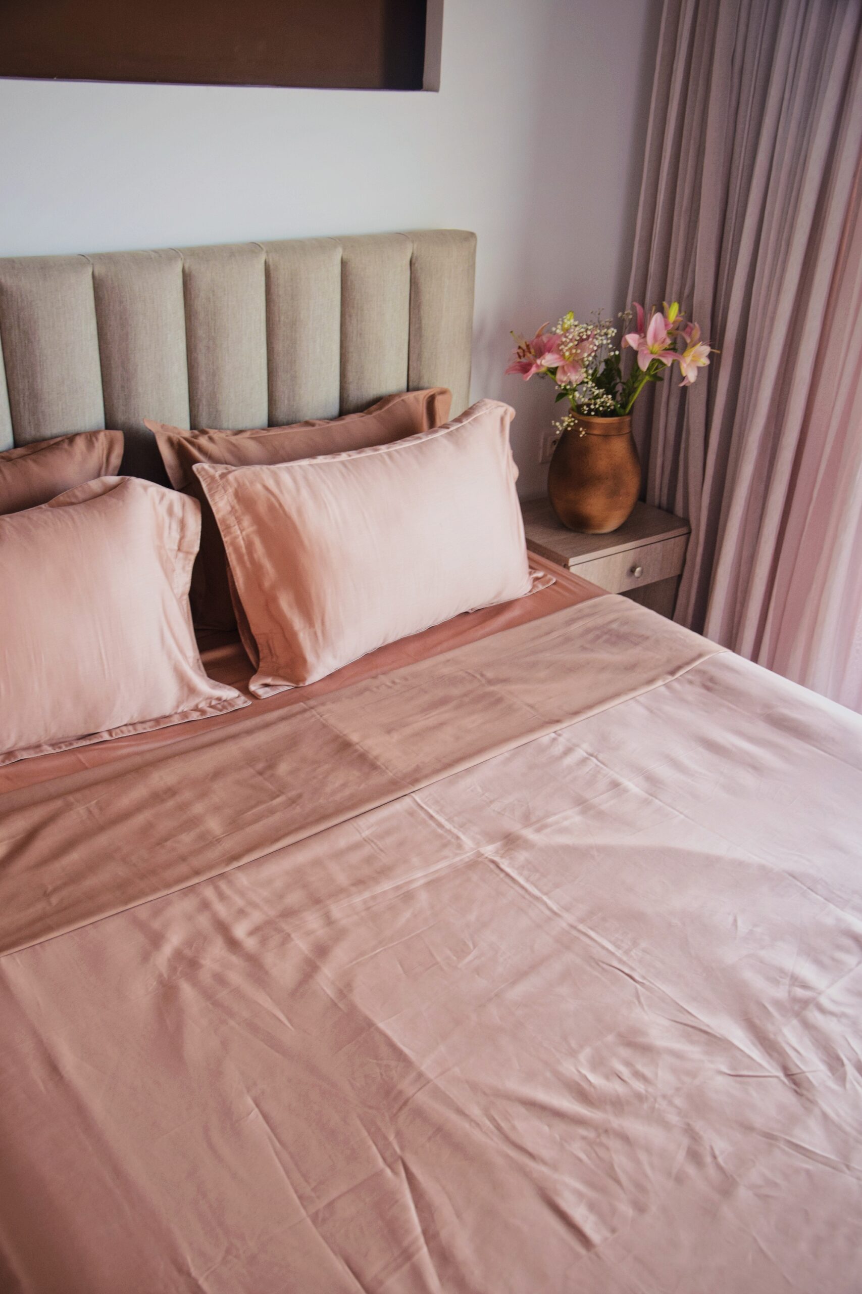 Parure de lit satin rose poudré et terracotta bicolore sur lit avec fleurs
