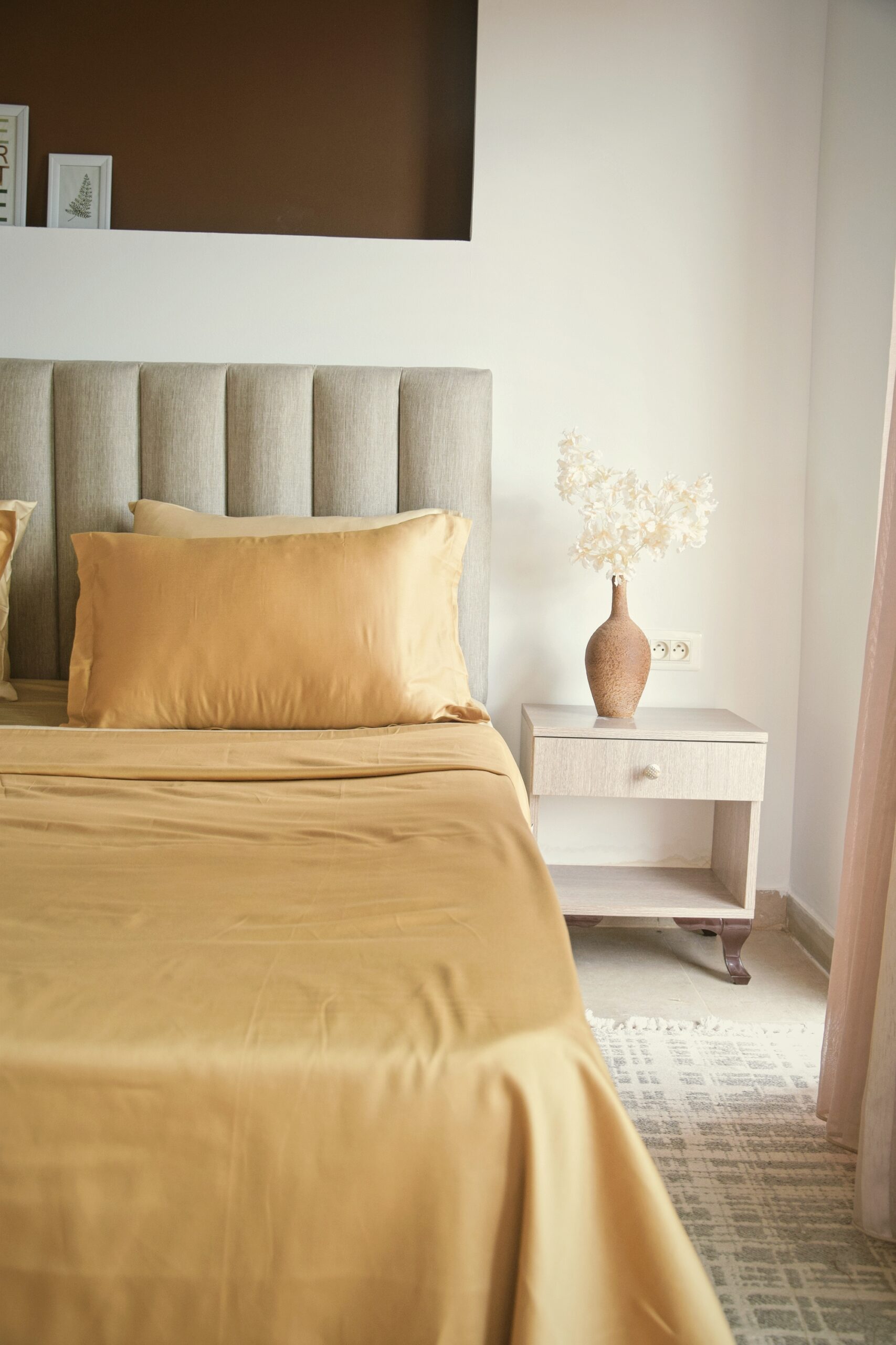 Parure de lit en satin doré moutarde sur lit avec tête de lit beige