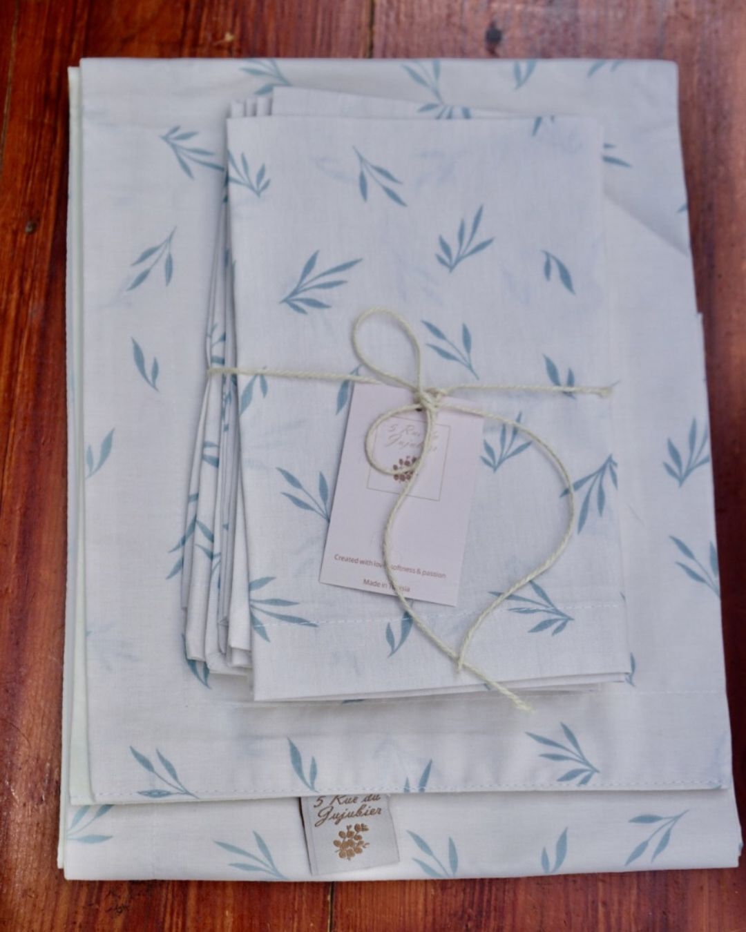 Chemin de table et serviettes en coton motif feuillage bleu-vert, pliés et noués